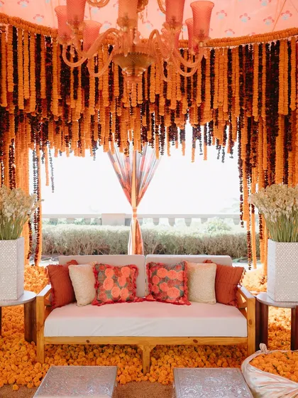 A stunning photo backdrop made entirely of marigolds, framing a comfortable seating area for the couple. We design key photo opportunities within the decor for you and your guests.