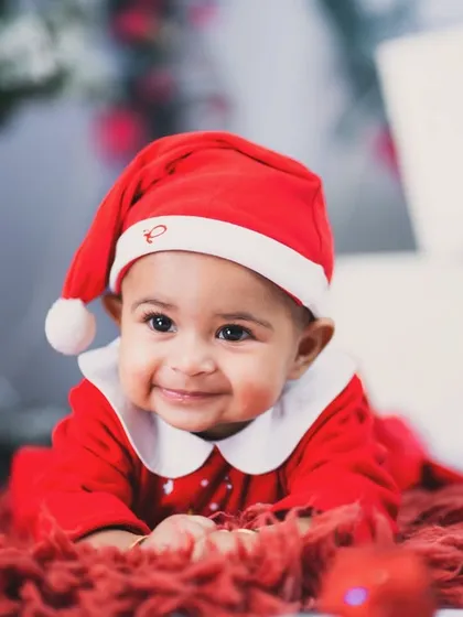 The most wonderful time of the year. This little Santa's helper has the sweetest smile, surrounded by presents under the Christmas tree.