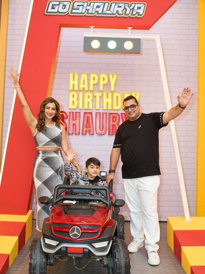 The happy family waves from the custom-designed photo booth, complete with a mini car and a "Happy Birthday" sign.