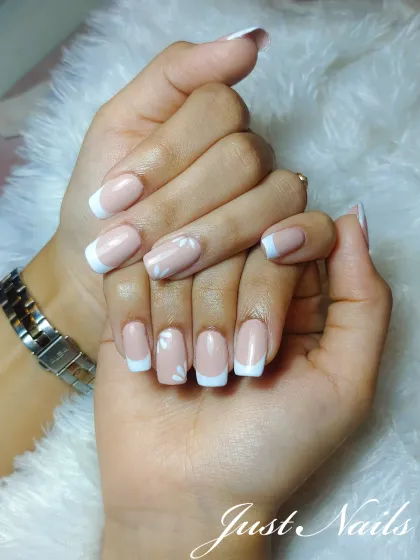 A simple and elegant French manicure on short, square nails with a delicate white floral accent.