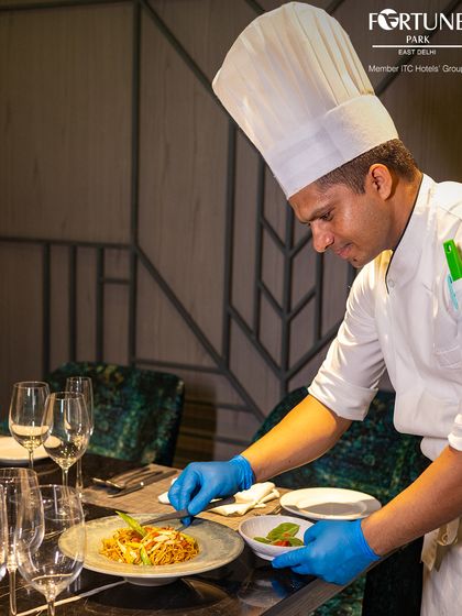 Our chef adds a delicate garnish to a plate of noodles, showcasing the attention to detail that goes into every dish we serve.