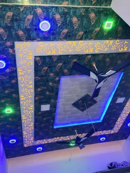 A bold and decorative PVC ceiling design. The use of patterned panels with peacock feather motifs and multi-colored lights creates a vibrant and unique look.