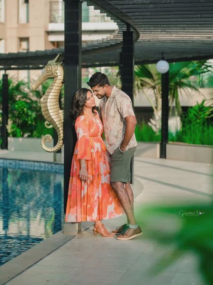 A relaxed and stylish poolside shoot. The lush green surroundings and calm water provide a beautiful, resort-like setting for casual and romantic couple photos.