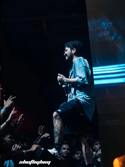 Encore ABJ from Seedhe Maut stands on the stage barrier, getting up close with the crowd. This image captures the direct and intense connection they have with their fans.