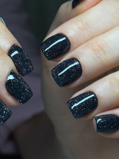 A sophisticated black glitter manicure. The fine silver glitter suspended in the black polish gives the look of a sparkling night sky.