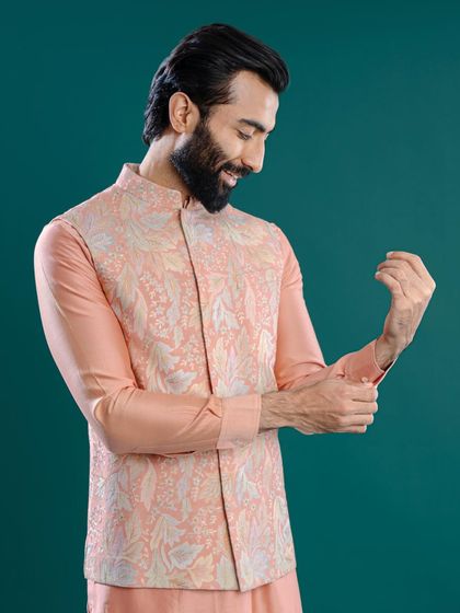 A study in pastel perfection. This peach-toned Jawahar jacket features delicate, tone-on-tone leaf embroidery, creating a subtle yet sophisticated look for a daytime celebration.