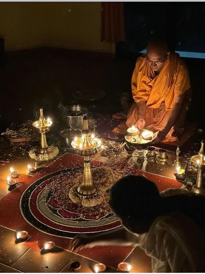 A swami performs a ritual during a puja, surrounded by lamps. These ceremonies are a profound opportunity for spiritual immersion.