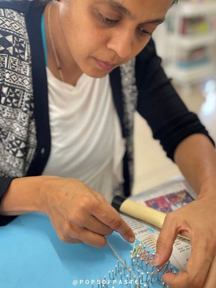 This artist is deeply engaged in weaving the threads for her design, demonstrating the calming nature of string art.
