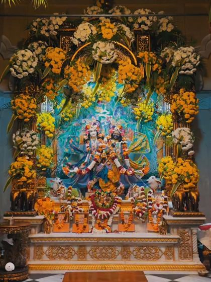 An elaborate and stunning floral decoration for a temple deity. The entire shrine is framed with an abundance of fresh yellow and white flowers, creating a divine look.
