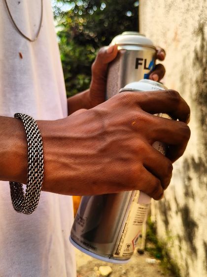 A close-up of my hands holding two spray cans. These are the primary tools of my trade, and I always have them with me, ready for the next wall.