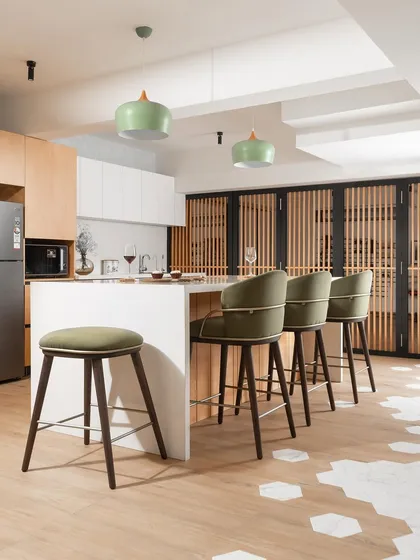 For this basement apartment, we designed an open kitchen with a large island that doubles as a breakfast bar. Light wood cabinetry, white countertops, and pops of green from the pendant lights and bar stools help to make the space feel bright and airy.