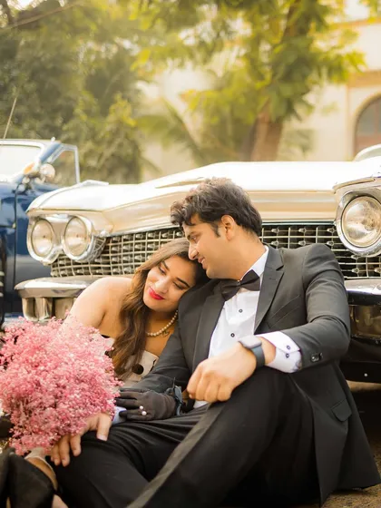 A romantic moment with a vintage Cadillac. The combination of classic formalwear, a beautiful vintage car, and the soft, warm tones creates a dreamy, nostalgic, and incredibly stylish pre-wedding photograph.
