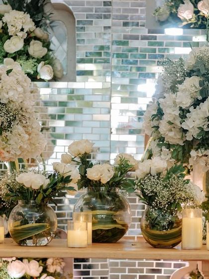 The floral details bring this enchanted forest wedding to life. A collection of white hydrangeas and roses in glass vases, surrounded by glowing candles against a mirrored tile wall, creates a dreamy escape.