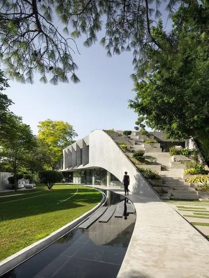 The completed Villa KD 45, where the architecture emerges from the landscape. The design prioritizes a connection to nature, with a cascading green roof and seamless transitions between indoor and outdoor spaces, creating a private, biophilic sanctuary.