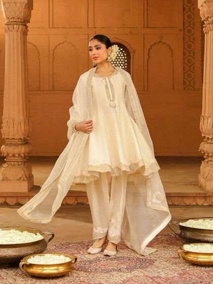 A lovely ivory anarkali with a scalloped hem, a graceful and feminine silhouette for any celebration.