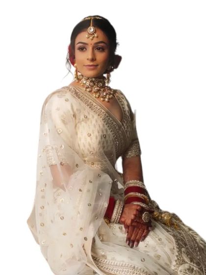 A clean, minimalist shot of the bride in her white lehenga. The makeup is elegant and understated, perfect for a modern wedding.