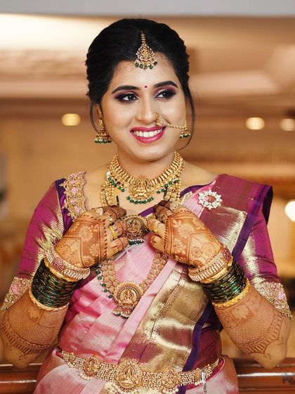 A happy bride showing off her stunning temple jewelry, which is perfectly complemented by her traditional mehendi.