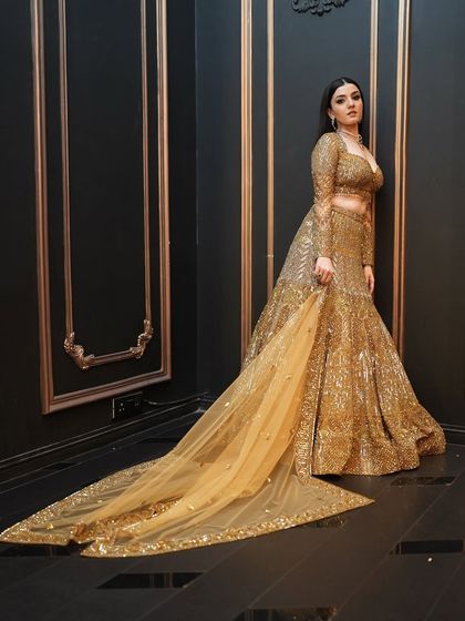 The dramatic trail of the golden lehenga adds to the grandeur of the look. The makeup is kept bold and glamorous to match.
