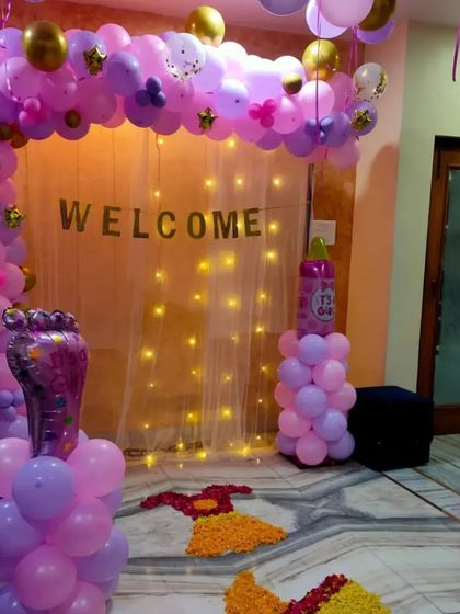 The entrance for the "Welcome Girl" party, featuring a purple and pink balloon arch, fairy lights, and a flower petal pathway.