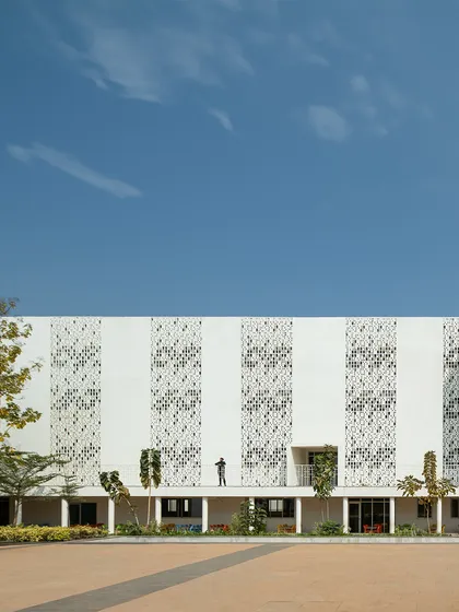 The facade of Vidyashilp Academy is a study in material intelligence. The large 'jaali'-inspired panels are not just decorative; they filter sunlight, maintain privacy, and ensure constant airflow, elevating simple materials into purposeful elements of climate-responsive design.