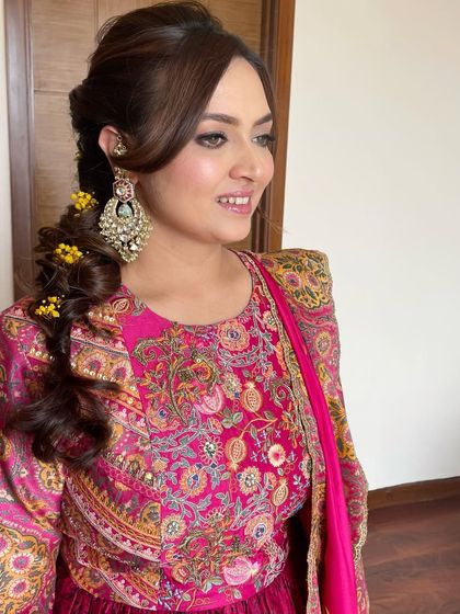 A side profile showing the messy braid adorned with flowers, a perfect hairstyle for a fun and festive Mehendi.