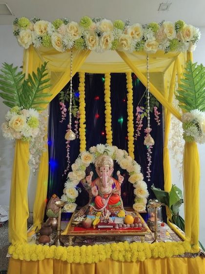 A yellow-themed mandap perfect for a Haldi ceremony or Ganpati puja. The design features a yellow canopy, a dark blue backdrop, and garlands of yellow flowers.