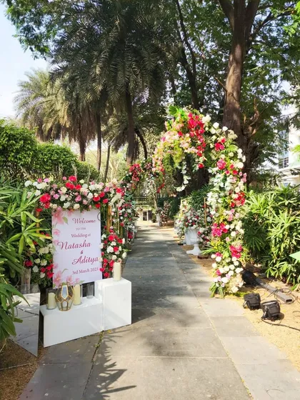 A beautiful floral pathway for an outdoor wedding, with lush arches of red, pink, and white flowers guiding guests to the ceremony.