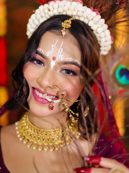 A close-up of Radha's smiling face, showing the intricate white paintwork and jewelry.