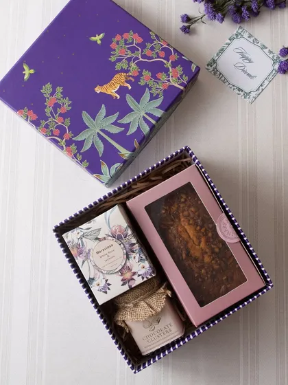 A perfect example of a compact yet complete gift. This box includes a tea cake, a jar of chocolate clusters, and a small decorative item, all beautifully arranged.