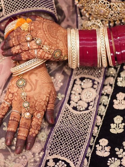 The final henna stain, beautifully adorned with the bride's chooda bangles. The design details remain sharp and clear, even after the paste is removed.