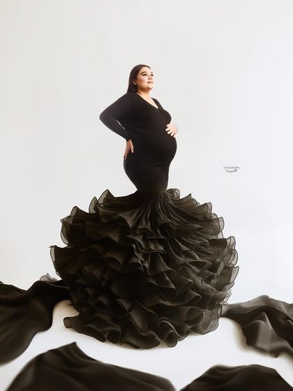 A powerful stance in a dramatic black ruffled gown. The way the fabric spreads across the floor creates a stunning visual effect, making for a very memorable maternity photo.