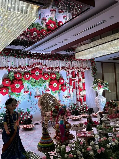 An angled view of the red and white floral stage, showing the crystal chandeliers and the elaborate offering table.
