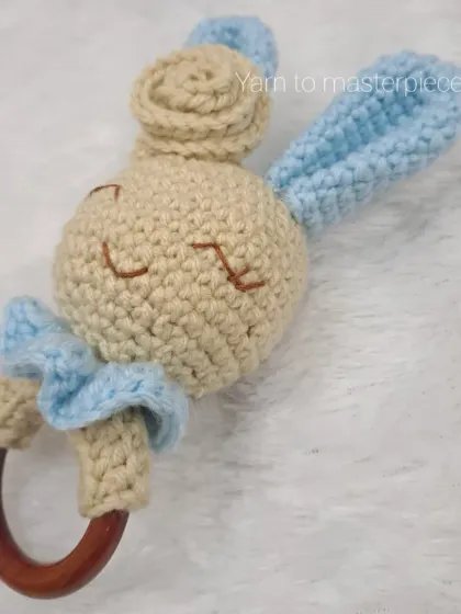 This bunny rattle is made with a smooth wooden teething ring, perfect for soothing sore gums. The head is adorned with a frilly blue collar.