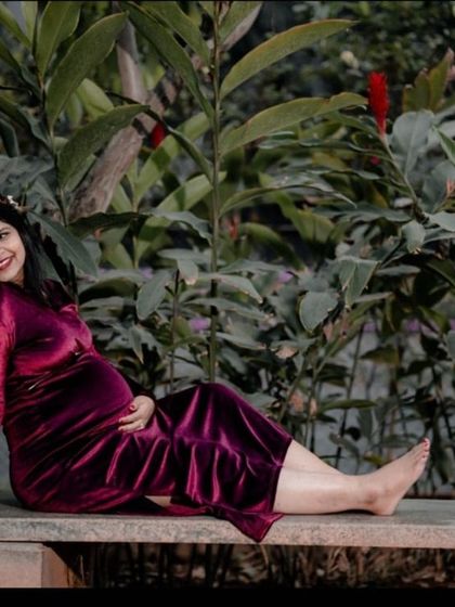 A full-length shot of an expectant mother relaxing on a park bench. The natural setting and her comfortable pose create a peaceful and serene image.