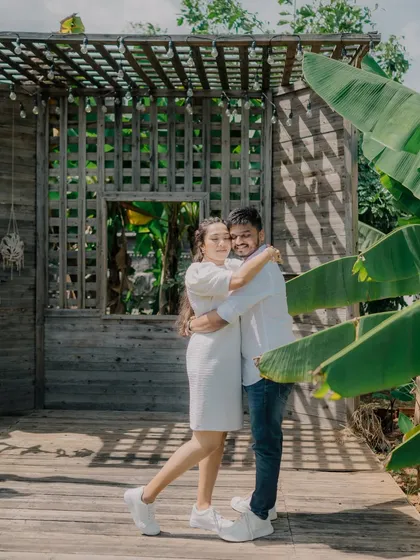 A happy, relaxed portrait from a pre-wedding shoot at a resort. The rustic wooden backdrop and lush greenery create a warm and inviting atmosphere.