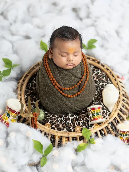 This 2.5-month-old baby boy is beautifully wrapped and posed as a sleeping Shankara, surrounded by symbolic props.