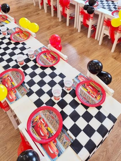 The kids' tables at the Cars party, complete with checkered runners, themed plates and cups, and balloon decorations.