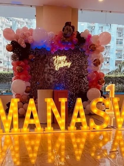 A Minnie Mouse stage with a sequin backdrop, 'Happy Birthday' neon sign, and large marquee letters.