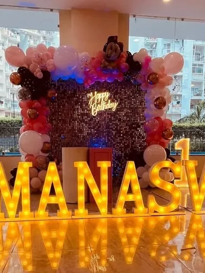 A Minnie Mouse stage with a sequin backdrop, 'Happy Birthday' neon sign, and large marquee letters.