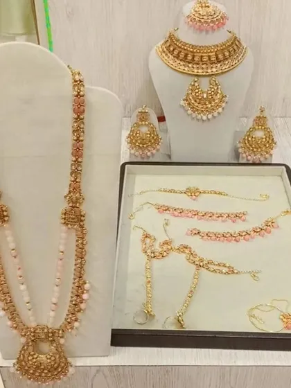 This antique gold and pastel pink bead jewellery set is perfect for a soft, romantic look. It comes with a choker, rani haar, and matching accessories.