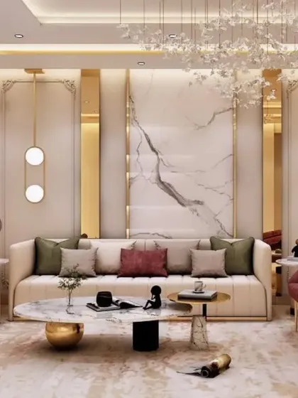 This living room is the epitome of luxury, featuring a plush cream sofa accented with deep red armchairs and gold detailing. The design incorporates a marble feature wall, ornate pendant lighting, and classic wall molding to create a space of timeless sophistication.