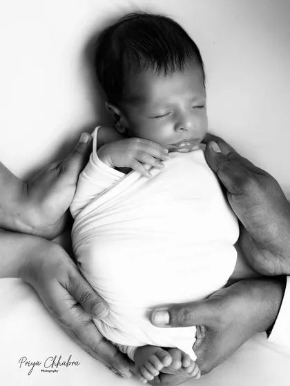 A newborn baby held safely in the hands of their parents. This powerful black and white photo symbolizes the love, hope, and new beginnings that a new life brings.