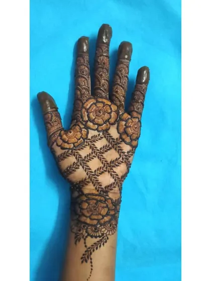 A similar design concept with a leafy jaal pattern and detailed floral work. The filled-in fingertips complete this festive look.