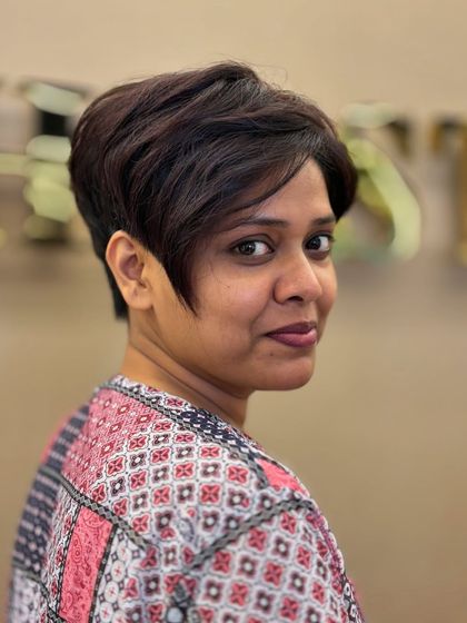 A stunning, sharp pixie cut with longer, side-swept bangs. This look is edgy, confident, and beautifully frames the client's face.