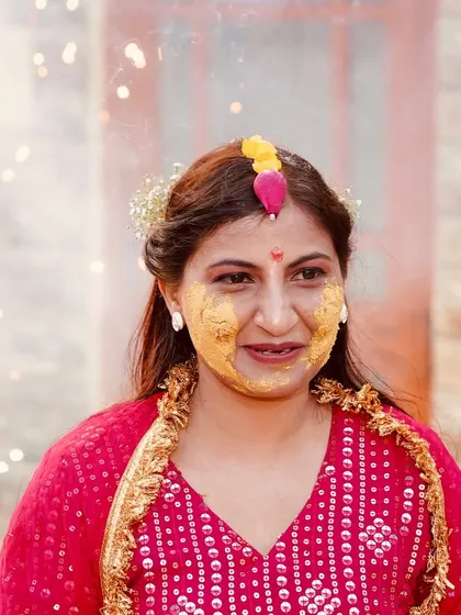 Another candid portrait from the haldi ceremony, capturing a natural smile. The background sparklers add a festive atmosphere to the photograph.