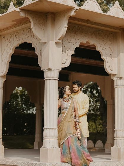 A quiet portrait of the couple during their Haldi ceremony. This image showcases the beautiful details of their coordinated outfits and the intricate architecture of the venue.