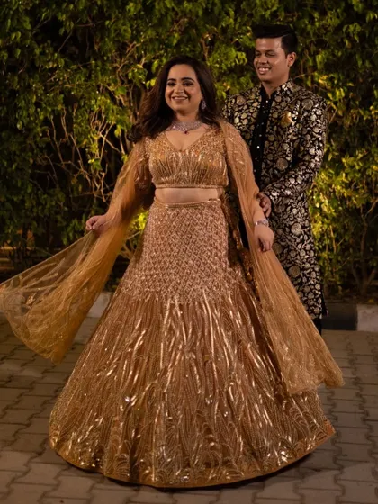Our bride Shivali glowing at her sangeet. This gorgeous lehenga with a warm orange undertone and sparkling gold work was chosen to complement her skin tone and make her shine on the dance floor.