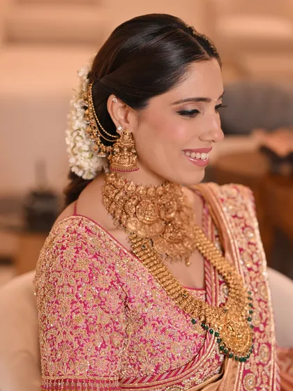 A side profile of the traditional South Indian braid, showing how it is elegantly paired with temple jewelry and a smile.