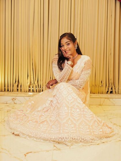 A full shot of the client seated in the white chikankari lehenga.