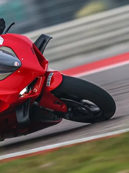 A rider on a red Ducati Panigale focuses on hitting the apex perfectly. Precision is key to a fast lap.